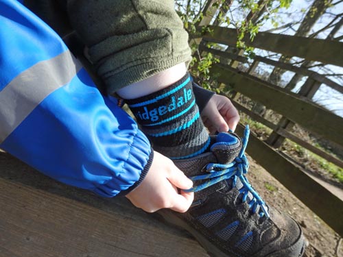 child tying his blue hiking shoe laces